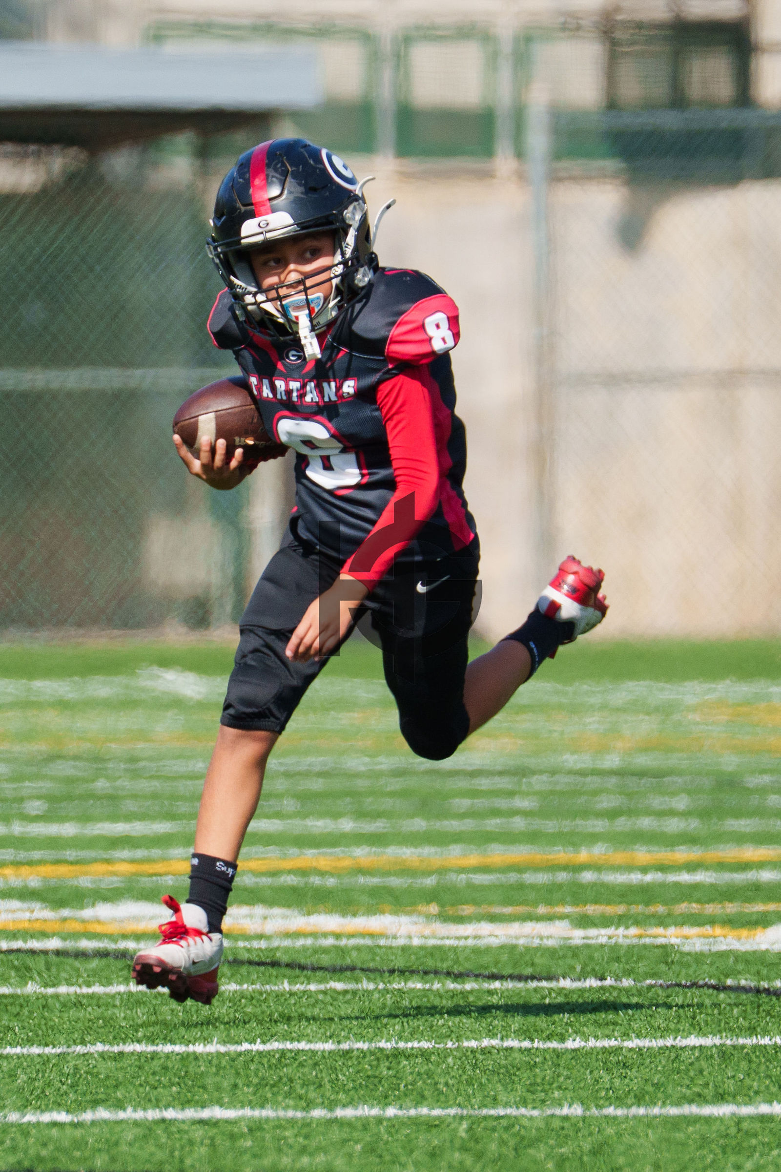 A quarterback scrambling with the ball in his right hand