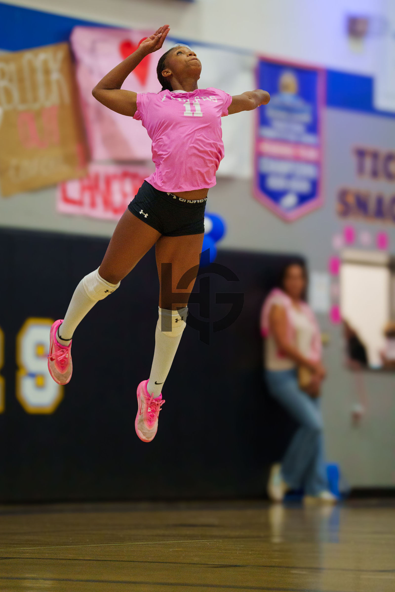 A player airborne during an attack with a scoreboard behind her